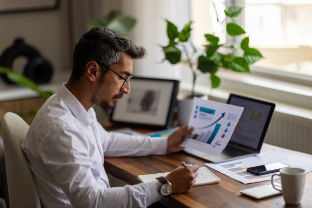 Businessman analyzing financial reports and corporate balance charts at his desk